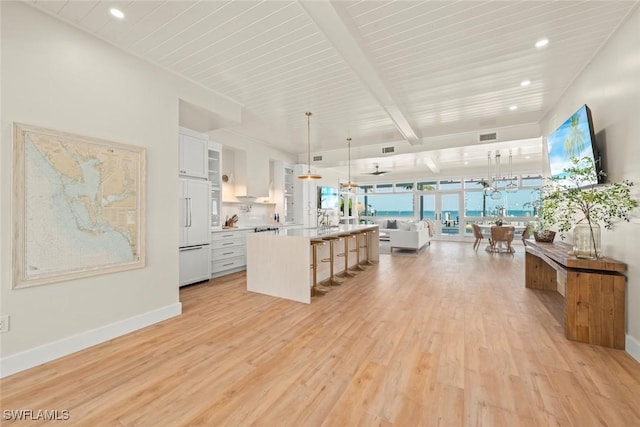 15009 Binder Dr, Captiva, FL 33924 - kitchen with open floor plan, paneled built in fridge, a breakfast bar area, light wood-type flooring, and white cabinetry