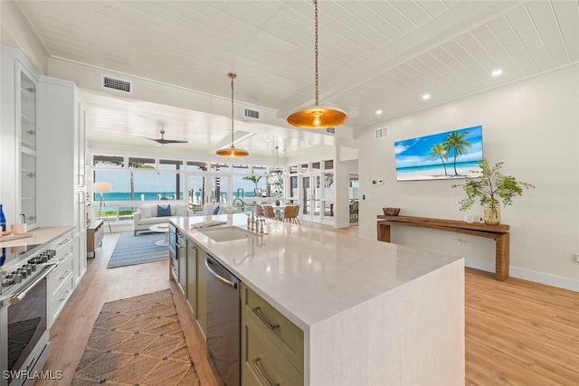 15009 Binder Dr, Captiva, FL 33924 - kitchen with appliances with stainless steel finishes, open floor plan, light wood-type flooring, a sink, and a center island with sink