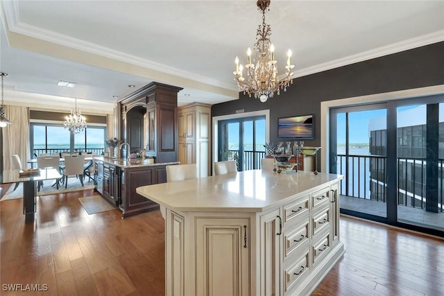 1920 Virginia Ave Unit 1602, Fort Myers, FL 33901 - kitchen with a chandelier, a kitchen island with sink, cream cabinetry, hardwood / wood-style floors, and crown molding
