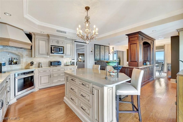 1920 Virginia Ave Unit 1602, Fort Myers, FL 33901 - kitchen with appliances with stainless steel finishes, custom range hood, a kitchen breakfast bar, a chandelier, and light countertops