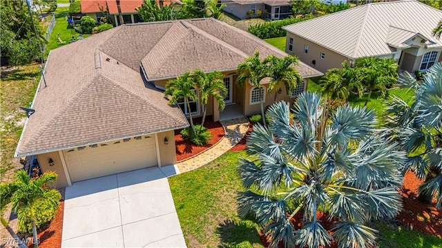 10630 Woodchuck Ln, Bonita Springs, FL 34135 - view of front of property featuring driveway, stucco siding, an attached garage, roof with shingles, and a front lawn