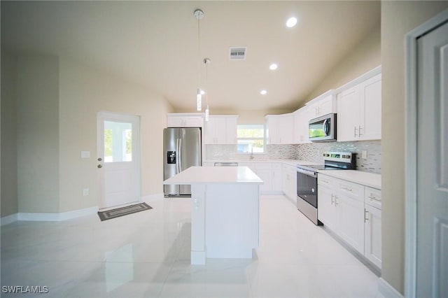 1893 Weldon Ave, Lehigh Acres, FL 33972 - kitchen with stainless steel appliances, vaulted ceiling, a center island, backsplash, and light countertops