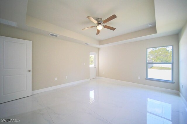 1893 Weldon Ave, Lehigh Acres, FL 33972 - spare room featuring ceiling fan, a raised ceiling, healthy amount of natural light, and baseboards