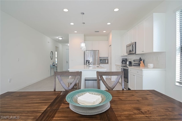 5536 Morino Way, Ave Maria, FL 34142 - kitchen with stainless steel appliances, a center island with sink, decorative backsplash, white cabinets, and recessed lighting