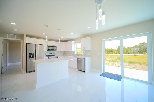 1895 Weldon Ave, Lehigh Acres, FL 33972 - kitchen with stainless steel appliances, decorative backsplash, a kitchen island, white cabinets, and light countertops