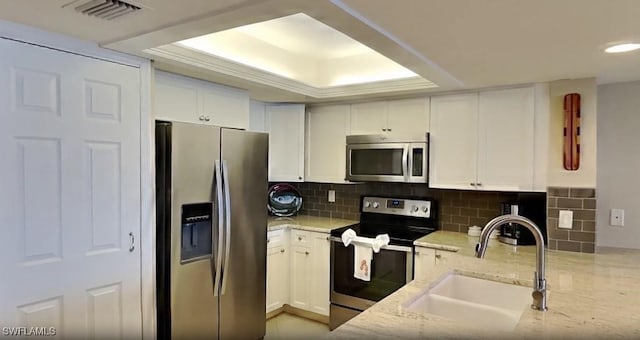 17170 Harbour Point Dr Unit 736, Fort Myers, FL 33908 - kitchen featuring stainless steel appliances, a sink, light stone counters, white cabinets, and a tray ceiling