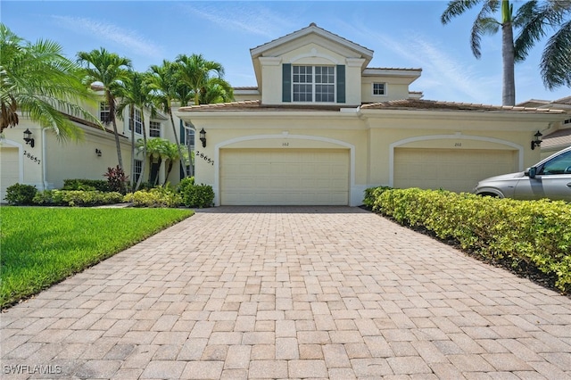 28657 San Lucas Ln Unit 102, Bonita Springs, FL 34135 - view of front of property with decorative driveway, a tiled roof, stucco siding, a front lawn, and an attached garage