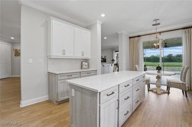 28657 San Lucas Ln Unit 102, Bonita Springs, FL 34135 - kitchen featuring light wood-style floors, crown molding, light countertops, white cabinetry, and a chandelier