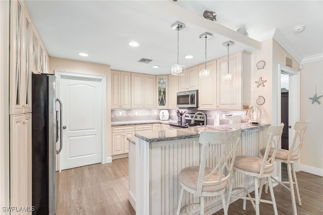 2608 NW 25th Ave, Cape Coral, FL 33993 - kitchen with stainless steel appliances, a peninsula, light wood finished floors, glass insert cabinets, and a breakfast bar area