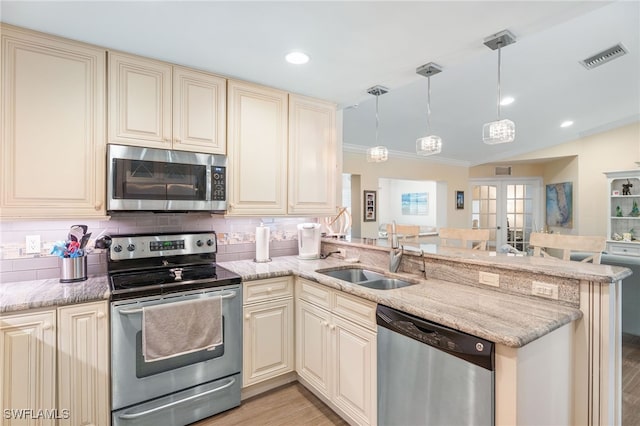 2608 NW 25th Ave, Cape Coral, FL 33993 - kitchen featuring stainless steel appliances, cream cabinets, a sink, a peninsula, and light wood finished floors