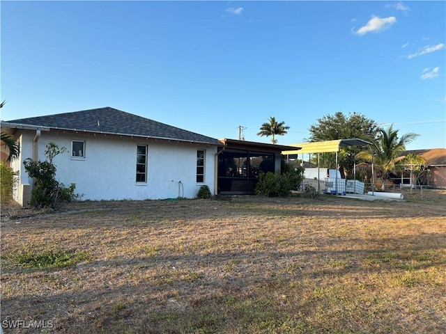 5504 Brookfield St, Lehigh Acres, FL 33971 - back of house featuring stucco siding, a sunroom, a yard, and roof with shingles
