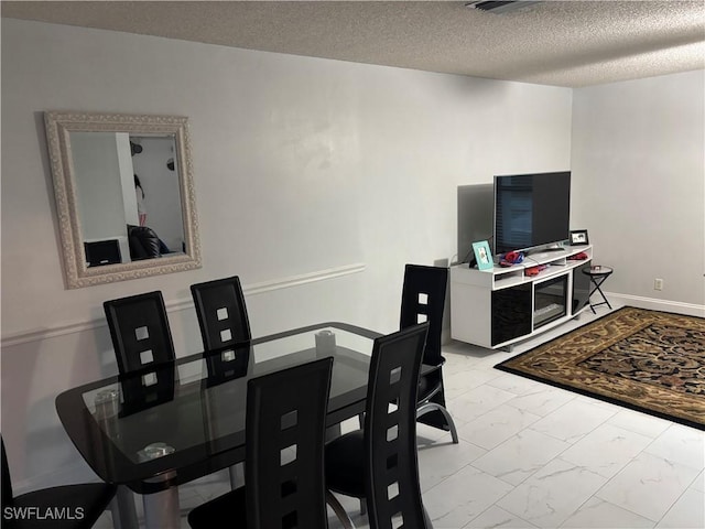 5504 Brookfield St, Lehigh Acres, FL 33971 - dining area featuring marble look tile flooring, a textured ceiling, and baseboards