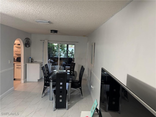 5504 Brookfield St, Lehigh Acres, FL 33971 - dining room with arched walkways, light marble finish flooring, and a textured ceiling