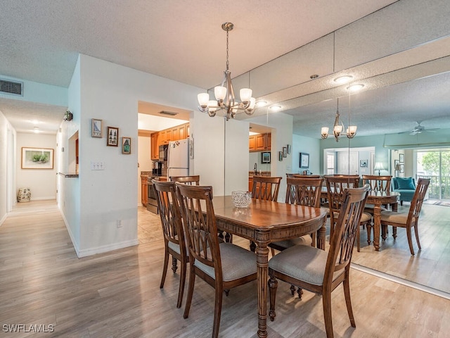 105 Tuscana Ct Unit 1002, Naples, FL 34119 - dining area with a chandelier, light wood-type flooring, a ceiling fan, baseboards, and a textured ceiling
