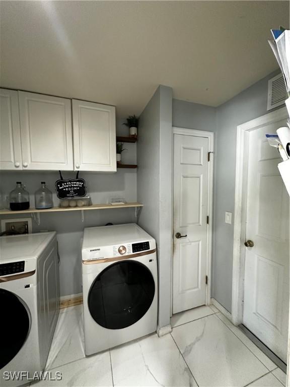 1839 Jovita Ave, Lehigh Acres, FL 33972 - washroom featuring independent washer and dryer, light marble finish floors, cabinet space, and baseboards