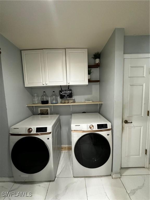 1839 Jovita Ave, Lehigh Acres, FL 33972 - laundry area featuring light marble finish flooring, washer and dryer, and cabinet space