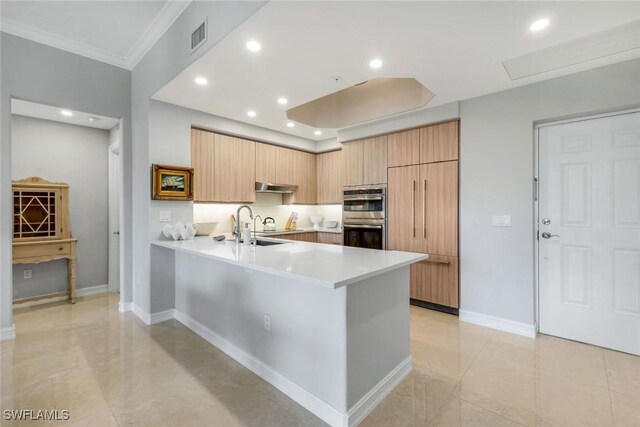 2728 Tiburon Blvd E Unit A403, Naples, FL 34109 - kitchen with double oven, light countertops, crown molding, a peninsula, and under cabinet range hood