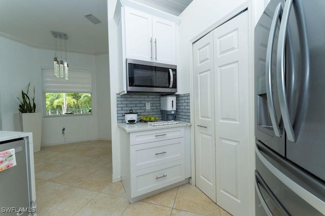 2140 8th St NE, Naples, FL 34120 - kitchen featuring appliances with stainless steel finishes, light tile patterned floors, light countertops, white cabinetry, and decorative backsplash