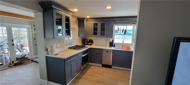 2685 Geary St, Matlacha, FL 33993 - kitchen with appliances with stainless steel finishes, gray cabinets, light wood finished floors, light countertops, and glass insert cabinets