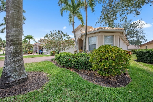 7384 Sika Deer Way, Fort Myers, FL 33966 - view of side of home featuring a lawn, a tile roof, stucco siding, and driveway