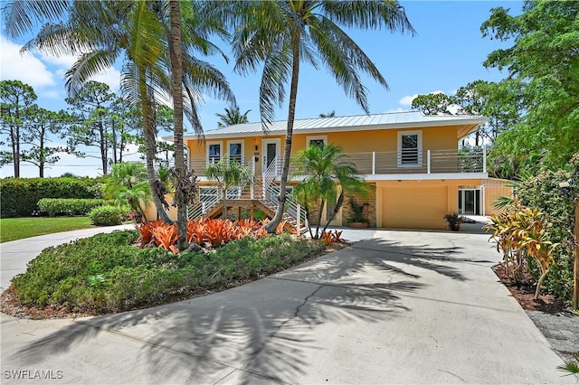 4680 Key Largo Ln, Bonita Springs, FL 34134 - view of front facade with concrete driveway, an attached garage, stairs, metal roof, and stucco siding