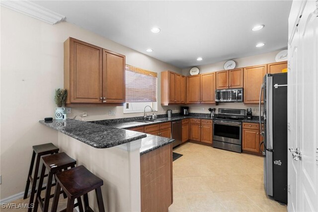 8364 Laurel Lakes Blvd, Naples, FL 34119 - kitchen with appliances with stainless steel finishes, a peninsula, a breakfast bar area, brown cabinets, and recessed lighting