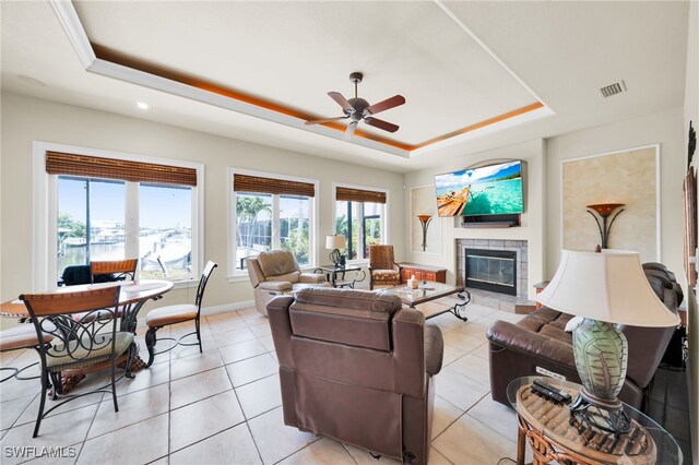 4009 Chiquita Blvd S, Cape Coral, FL 33914 - living room featuring a tray ceiling, a tiled fireplace, ceiling fan, baseboards, and light tile patterned floors