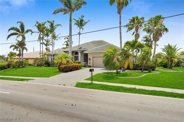 4009 Chiquita Blvd S, Cape Coral, FL 33914 - ranch-style home with a garage, driveway, stucco siding, a front lawn, and a tiled roof