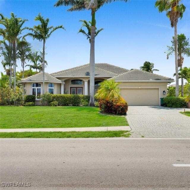 4009 Chiquita Blvd S, Cape Coral, FL 33914 - single story home with a tile roof, a garage, driveway, a front yard, and stucco siding