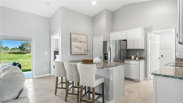 114 NW 6th Ter, Cape Coral, FL 33993 - kitchen with stainless steel fridge with ice dispenser, high vaulted ceiling, stone countertops, white cabinets, and a breakfast bar