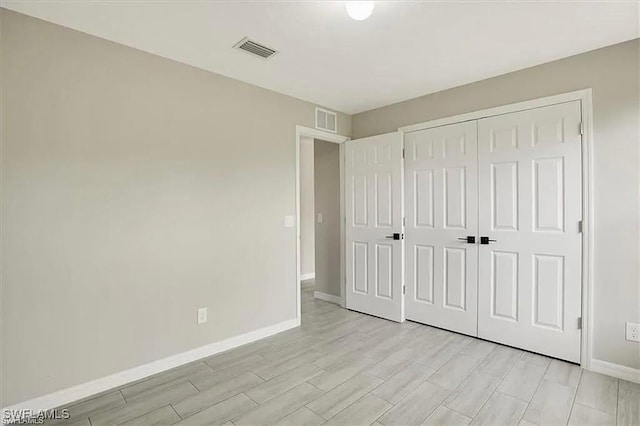 1143 Florence St E, Lehigh Acres, FL 33974 - unfurnished bedroom featuring baseboards, light wood-type flooring, and a closet