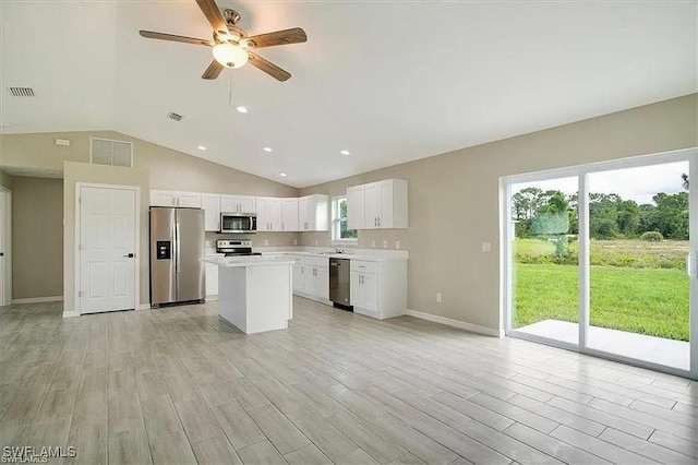 1143 Florence St E, Lehigh Acres, FL 33974 - kitchen with stainless steel appliances, a kitchen island, vaulted ceiling, light countertops, and light wood-type flooring