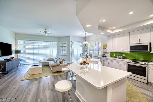 9232 Aviano Dr Unit 102, Fort Myers, FL 33913 - kitchen with electric stove, white microwave, a sink, open floor plan, and light wood-style flooring