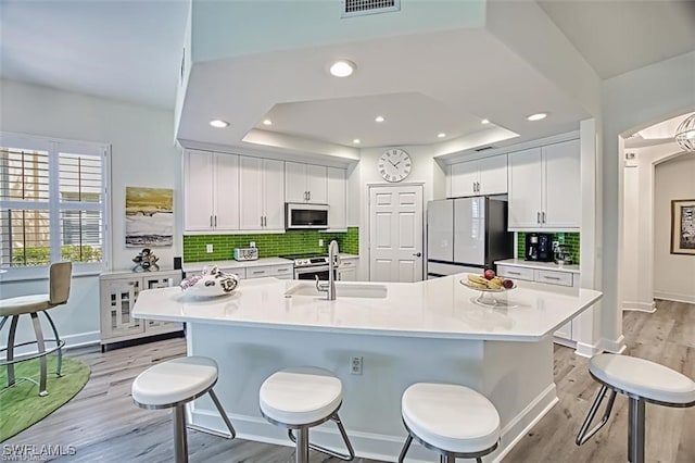 9232 Aviano Dr Unit 102, Fort Myers, FL 33913 - kitchen with stainless steel appliances, a sink, light wood-style floors, a breakfast bar, and decorative backsplash