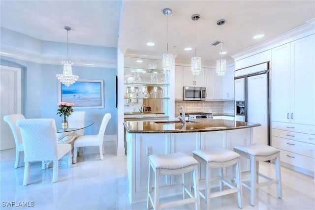 9115 Strada Pl Unit 5317, Naples, FL 34108 - kitchen with stainless steel microwave, built in refrigerator, dark stone countertops, decorative backsplash, and white cabinets