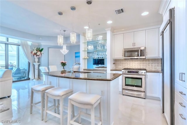 9115 Strada Pl Unit 5317, Naples, FL 34108 - kitchen featuring appliances with stainless steel finishes, backsplash, a kitchen bar, white cabinetry, and a sink