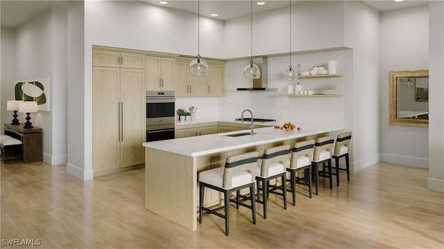 750 Goodlette-Frank Rd N Unit 301, Naples, FL 34102 - kitchen featuring a kitchen bar, a peninsula, wall chimney range hood, light wood finished floors, and a high ceiling