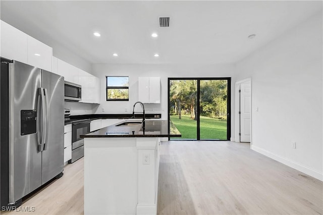618 Sheldon Ave, Lehigh Acres, FL 33936 - kitchen with stainless steel appliances, a sink, white cabinets, an island with sink, and light wood finished floors