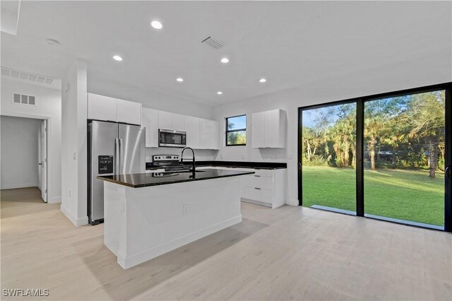 618 Sheldon Ave, Lehigh Acres, FL 33936 - kitchen featuring appliances with stainless steel finishes, dark countertops, light wood-style floors, a center island with sink, and recessed lighting