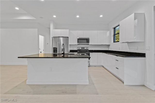 618 Sheldon Ave, Lehigh Acres, FL 33936 - kitchen featuring stainless steel appliances, white cabinets, dark countertops, a sink, and a kitchen island with sink