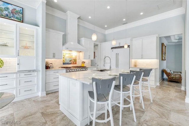 491 Wedge Dr, Naples, FL 34103 - kitchen with built in refrigerator, ornamental molding, wall chimney exhaust hood, tasteful backsplash, and a kitchen island with sink