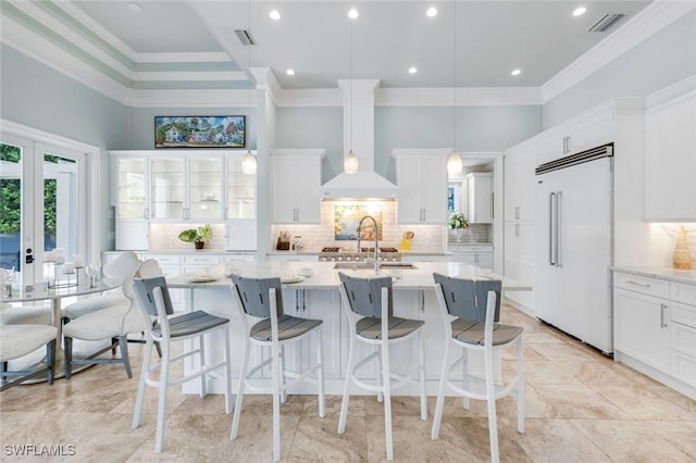 491 Wedge Dr, Naples, FL 34103 - kitchen featuring built in fridge, crown molding, an island with sink, decorative backsplash, and white cabinetry