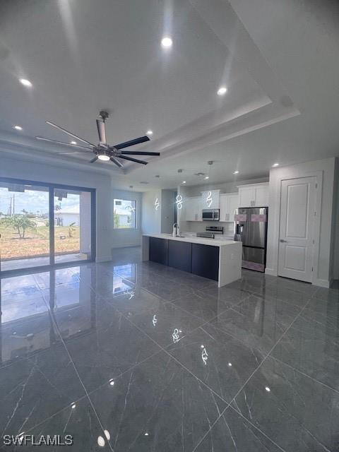 31 Kismet Pkwy E, Cape Coral, FL 33909 - kitchen with stainless steel appliances, light countertops, white cabinetry, a raised ceiling, and a large island with sink