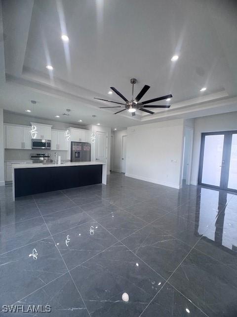 31 Kismet Pkwy E, Cape Coral, FL 33909 - unfurnished living room featuring a raised ceiling, ceiling fan, baseboards, and dark marble finish flooring