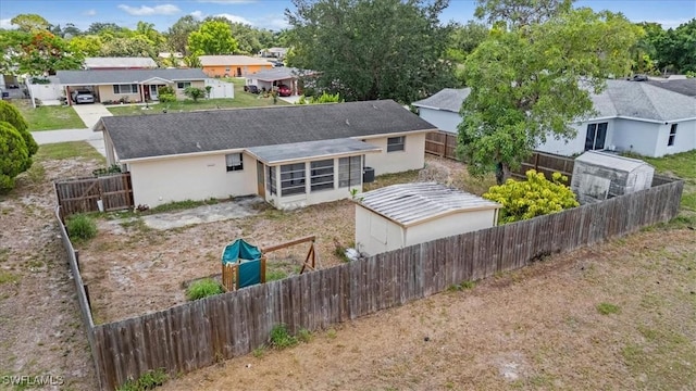 416 Rushmore Ave S, Lehigh Acres, FL 33936 - back of property featuring a sunroom, a fenced backyard, and stucco siding