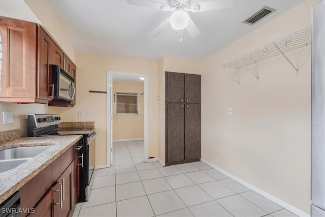 416 Rushmore Ave S, Lehigh Acres, FL 33936 - kitchen with appliances with stainless steel finishes, a ceiling fan, baseboards, light stone counters, and light tile patterned floors