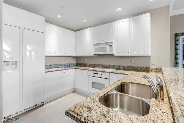 900 5th Ave S Unit 302, Naples, FL 34102 - kitchen with white appliances, a sink, light stone counters, white cabinets, and light tile patterned floors