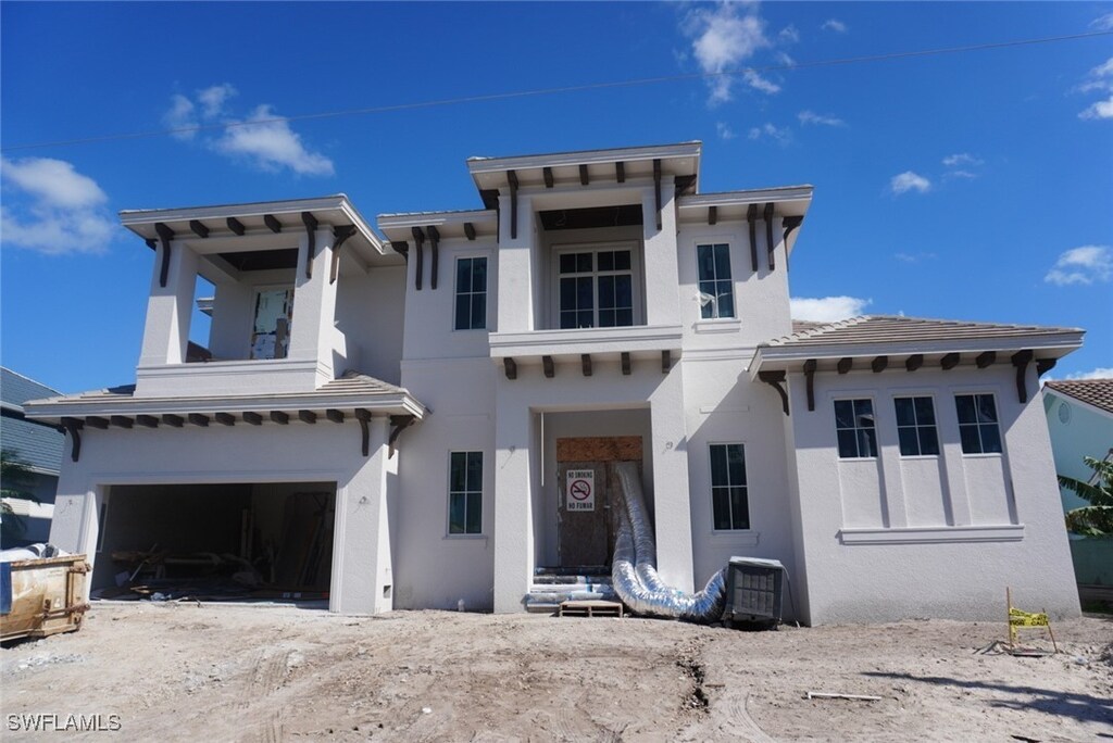 860 Banyan Ct, Marco Island, FL 34145 - view of front of house with stucco siding, a tile roof, a garage, and central AC unit