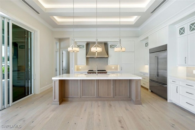 954 Sundrop Ct, Marco Island, FL 34145 - kitchen with stainless steel built in fridge, wall chimney range hood, decorative backsplash, light wood-type flooring, and light countertops
