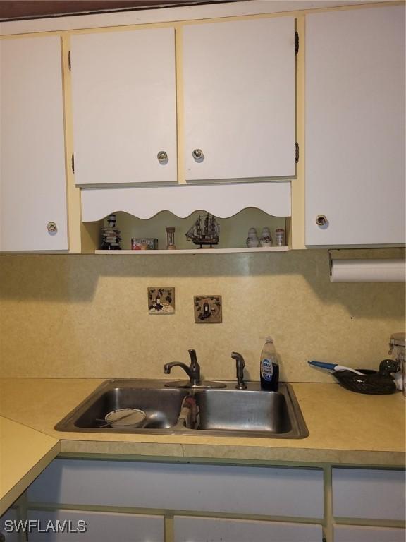 1104 Gulf St, Moore Haven, FL 33471 - kitchen view of open shelves, a sink, backsplash, light countertops, and white cabinets